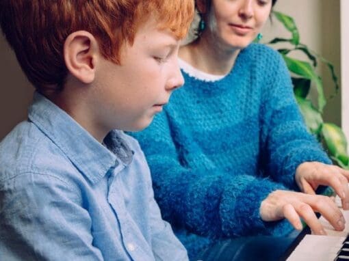 Lady piano teacher teaching a boy to play piano.