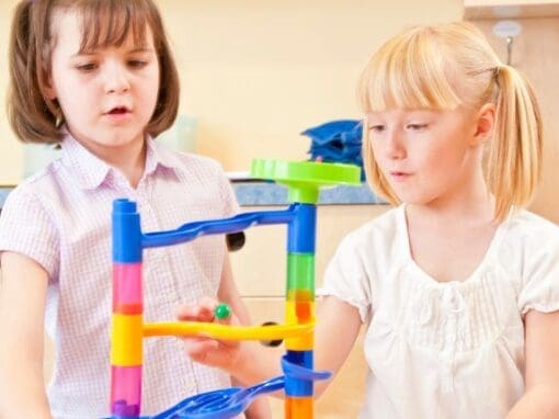 Two children playing with a marble run at nursery.